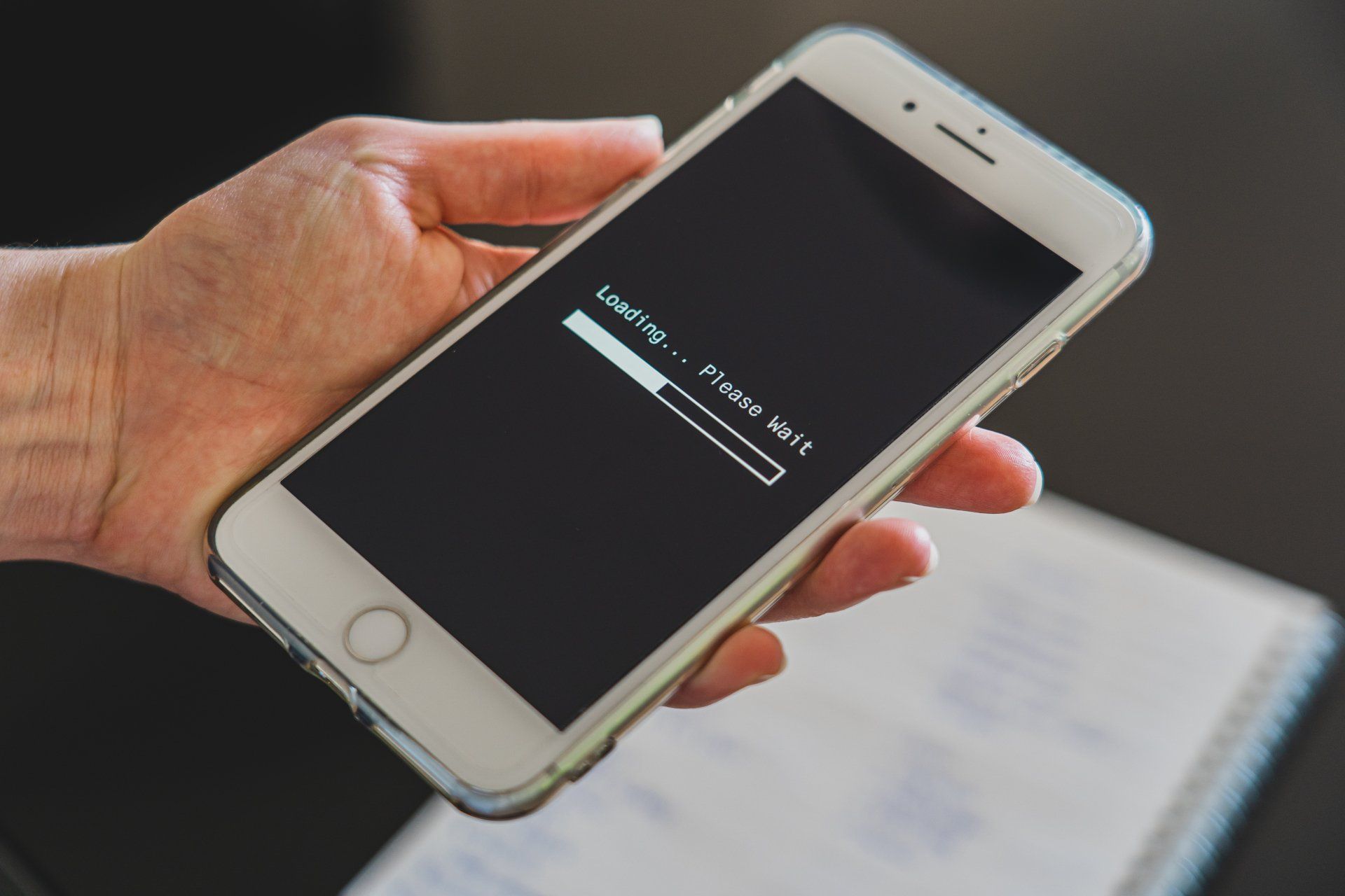 A hand holding a white smartphone with a loading bar on the screen